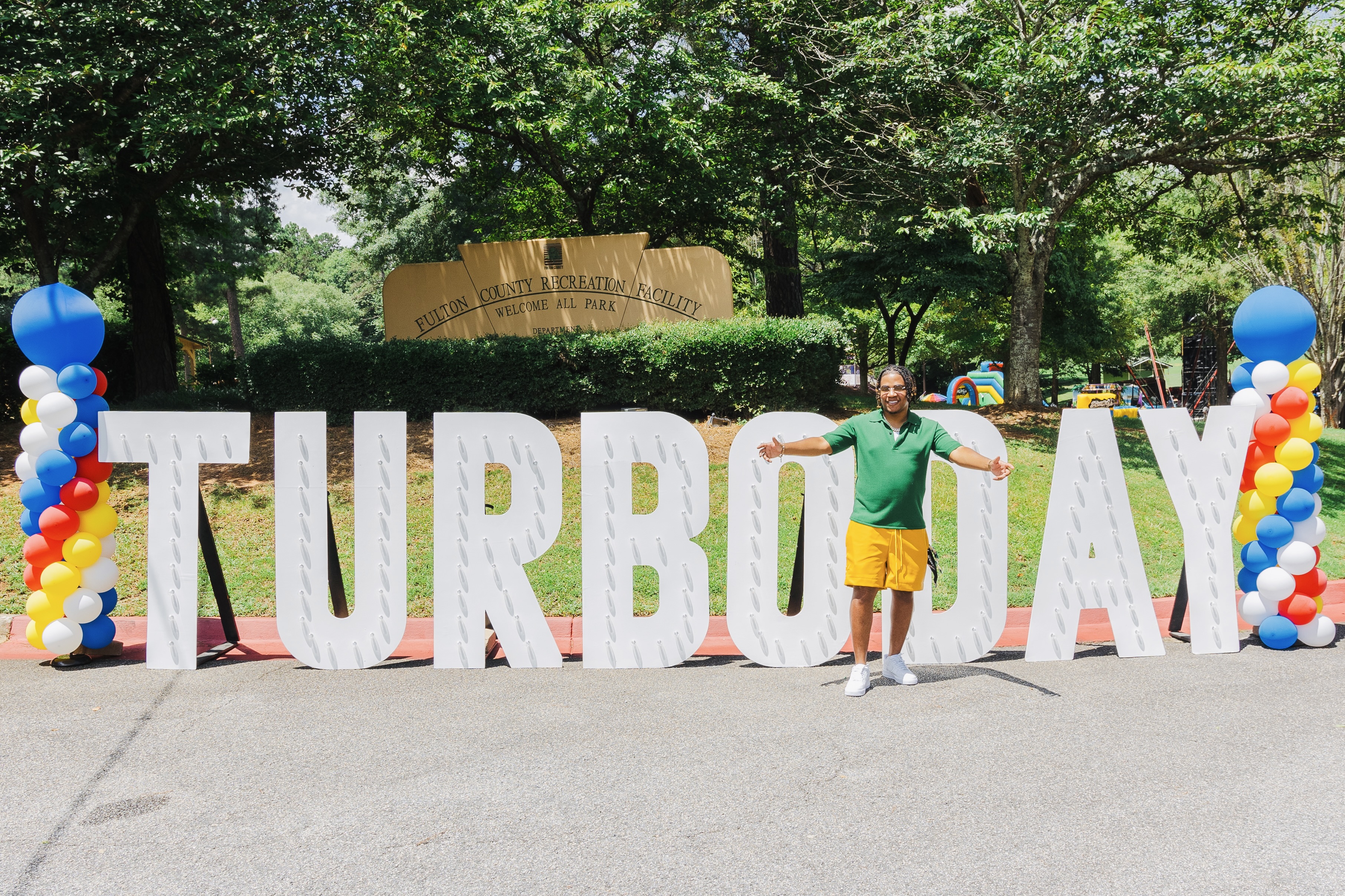 Turbo standing in front of Turbo Day sign at Welcome All Park, 2024